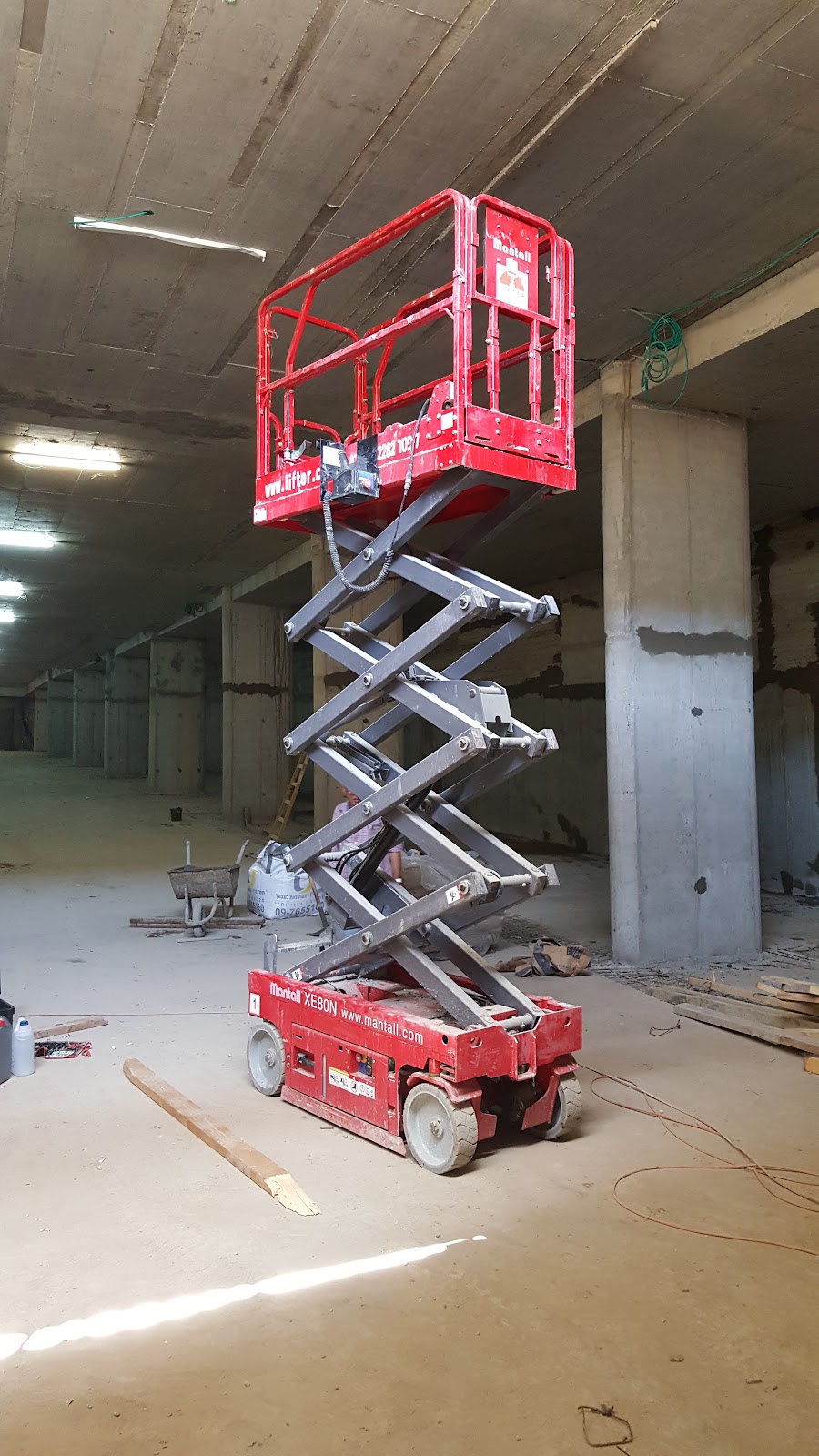 במת הרמה מספריים אדומה עומדת במקום בנייה מקורה וריקה, כשחלקיה מורמים.